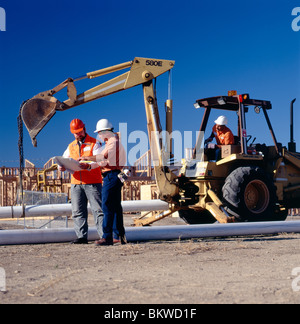 Schwere Ausrüstung Betreiber und Techniker installieren eine Wasserleitung in einer neuen Heimat Entwicklung. Stockfoto