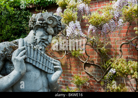 Pan Statue mit Glyzinien Wand Hintergrund an der RHS Wisley Gardens, Surrey, England Stockfoto