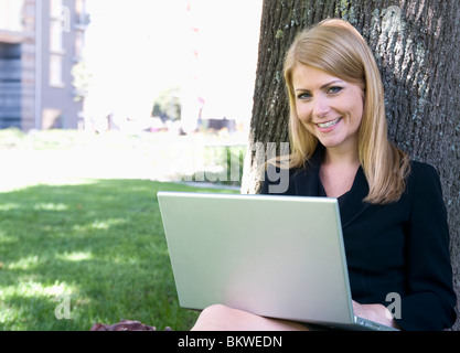 Geschäftsfrau sitzt im Park mit Laptop Stockfoto