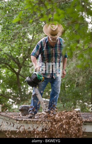 Mann mit Gas powered Laubbläser Blätter aus seinem Dach löschen Stockfoto