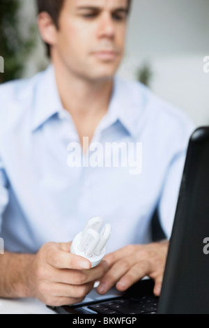 Mann mit Laptop mit einem Niedrigenergie-Birne in der Hand sitzt Stockfoto