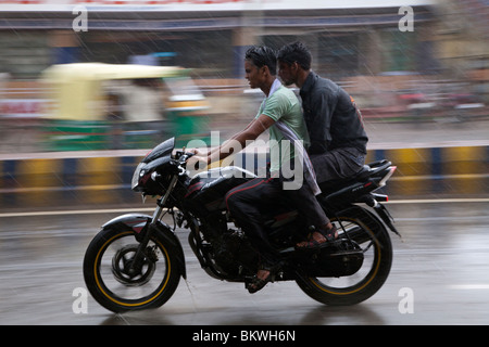 Indien, Uttar Pradesh, Agra, Motorradfahrer und Beifahrer im schweren Monsun-Regen Stockfoto