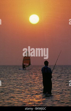 Ein Windsurfer und Surf Fischer bei Sonnenuntergang in Laguna Madre auf South Padre Island, Texas Stockfoto