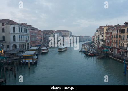 Blick von der Rialto-Brücke des Canal Grande und am Flussufer Gebäude mit der Vaporettos und festgemachten Gondeln in der Morgendämmerung Stockfoto