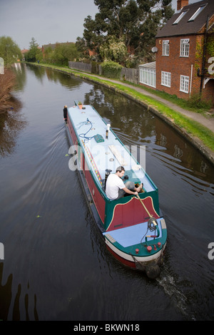 Ein Mann am Ruder eines Bootes schmal am Grand Union Canal, Loughborough, Leicestershire, England. Stockfoto