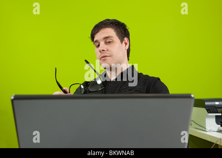Junger Mann sitzen im Büro und auf dem Laptop arbeiten Stockfoto