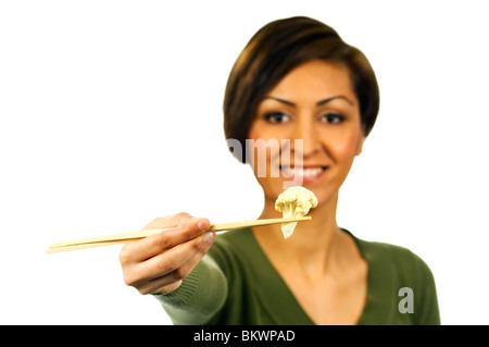 Lächelnde Frau hält ein Stück des gekochten Blumenkohl mit Stäbchen. Stockfoto