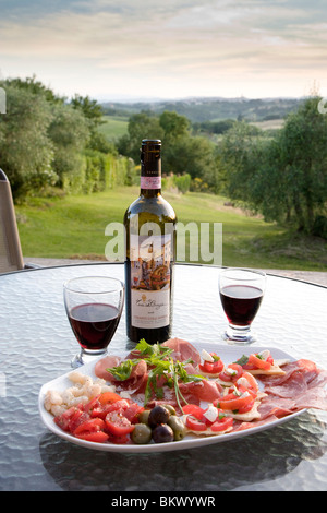 Antipasti mit Gläser Chiantiwein in einem italienischen Garten in der Toskana Siena in der Ferne Stockfoto