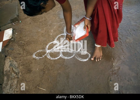 Eine Frau schmückt den Schritt ihres Hauses mit einem aufwendigen Design namens Rangoli als einen Akt der Hingabe, Swamimalai, Indien Stockfoto