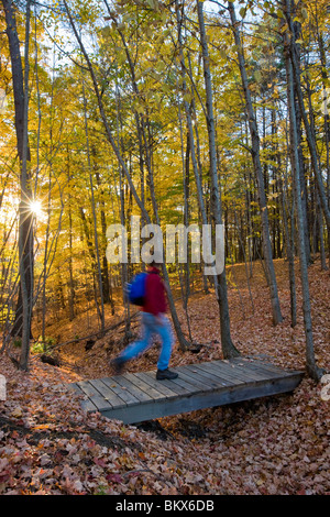 Ein Mann wandert über eine Fußgängerbrücke am Presumpscot-Fluss in Portland, Maine. Fallen. Stockfoto