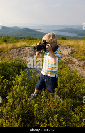 Ein kleiner Junge nimmt Bilder auf einem Hügel in Alton, New Hampshire. Stockfoto