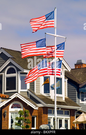 Fünf rote Fahnen weißen und blauen US-Welle in der Brise aus einem Fahnenmast vor einem Haus auf Balboa Island in Newport Beach, Kalifornien, USA. Stockfoto
