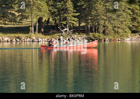 Ein Mann und eine Frau auf Lake Beauvert auf dem Gelände des Fairmont Jasper Park Lodge in einem roten Kajak Kajak Stockfoto