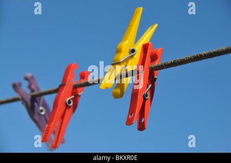 rote, gelbe und blaue Wäscheklammern an einer Wäscheleine. Stockfoto