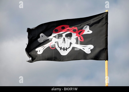 eine schwarze Pirat Schädel und gekreuzten Knochen Flagge, die von einem Mast. Stockfoto