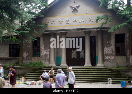 Markt mit frischen Lebensmitteln außerhalb eines alten Verwaltungsgebäude mit kommunistischen Stern und Mao Zedong sagte in der Zeche Stadt in Sichuan. Stockfoto