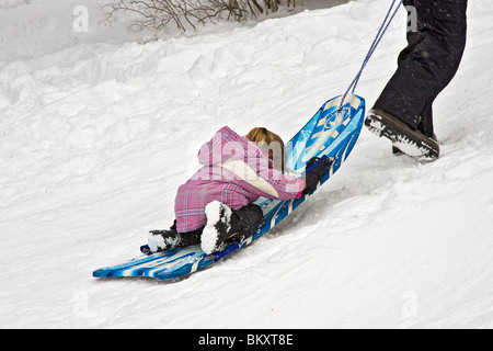 Kinder-Schlitten auf kurze Piste im Winter, South Lake Tahoe, Kalifornien, USA. Hier zieht ein Erwachsener ein junges Mädchen den Hügel hinauf. Stockfoto