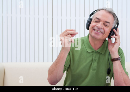 Häusliches Leben, ein senior Mann anhören von Musik mit geschlossenen Augen und Lächeln Stockfoto