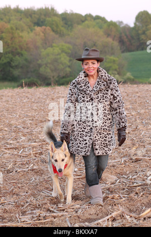 Hispanic Frau zu Fuß Hund im Winter fallen im Feld Stockfoto
