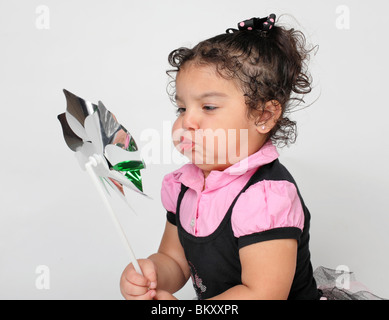 niedliche kleine hispanischen Mädchen spielen mit einem Spielzeug-Windrad im studio Stockfoto