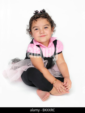 hübsches kleines Hispanic mexikanisches Mädchen im rosa Tutu auf weißem Hintergrund mit großen Lächeln auf ihrem Gesicht sitzen Stockfoto