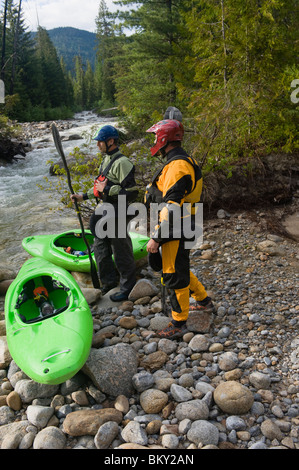 Zwei Wildwasser Paddler darauf vorbereiten, eine hohe Gebirgsbach Boot. Stockfoto