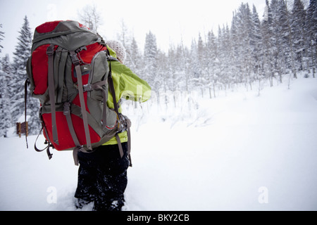 Eine junge Frau Wanderungen mit einem Rucksack im frischen Pulverschnee in den Wasatch Mountains, Utah. Stockfoto