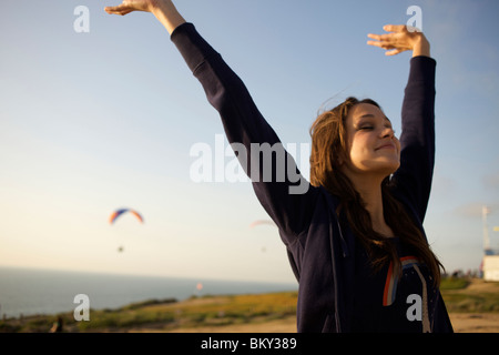 Frauen in ihren frühen 20er Jahren wirft ihre Arme und schließt die Augen um den Wind in einem Paragliding-Hafen in Kalifornien spüren. Stockfoto