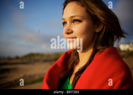 Frauen in ihren 20ern Sonnenbrille und in eine rote Decke gehüllt sieht den Blick von einem Hügel aus. Stockfoto