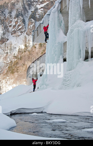 Ein Mann ist beim Klettern eine Eissäule auf einer Autobahn in Sounkyo Schlucht, Daisetsuzan Nationalpark, Hokkaido, Japan gesichert. Stockfoto