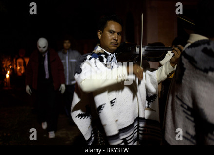 A Mariachi spielt seine Violine als Mann gekleidet geht eine Halloween-Kostüm hinter während des Tages der Toten in Mexiko-Stadt. Stockfoto