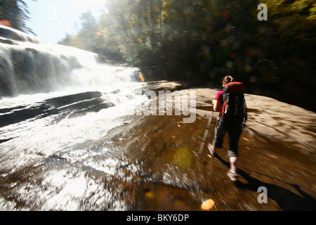 Bewegungsunschärfe der Frau zu Fuß am Fuße des Wasserfalls. Stockfoto
