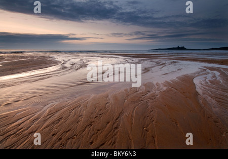 Morgendämmerung bricht über Dunstanburgh Castle von Embleton Bay Stockfoto