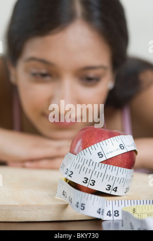 Maßband um einen Apfel vor einer Frau gewickelt Stockfoto