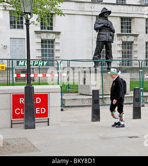 Ein Mann in das Kostüm eines Mannes Morris geht vorbei an der Statue von Feldmarschall Slim außerhalb des Gebäudes des Verteidigungsministeriums Stockfoto