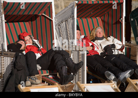 Menschen sitzen und Sonnenbaden im überdachten Strand Korbsessel auf der Terrasse des Popcorn Plaza, eine Schneebar am Laengfluh, Saas-Fee, V Stockfoto