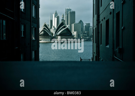 Sydney Opera House mit Stadt im Hintergrund über den Hafen am Ende einer ruhigen Straße entnommen. Stockfoto