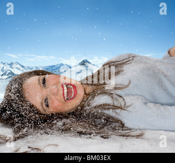 Lachende Frau legt in gefallenem Schnee Stockfoto