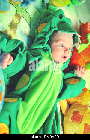 Junges Kindes Baby trägt ein Dinosaurier Kostüm und schaut überrascht. Stockfoto