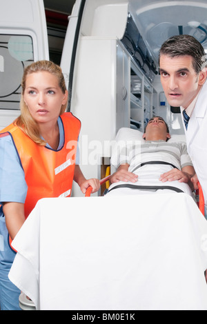 Führen eines Patienten auf eine Bahre von einem Krankenwagen Sanitäter Stockfoto