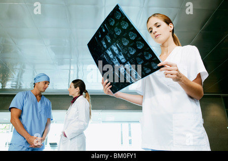 Krankenschwester untersucht ein Röntgenbild mit ihren Kollegen diskutieren im Hintergrund Stockfoto