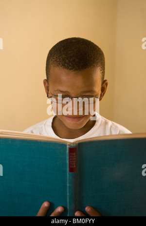 Jungen (8-9) Lächeln beim Lesen Buch, St. Francis Bay, Meer Vista, Provinz Eastern Cape, Südafrika Stockfoto