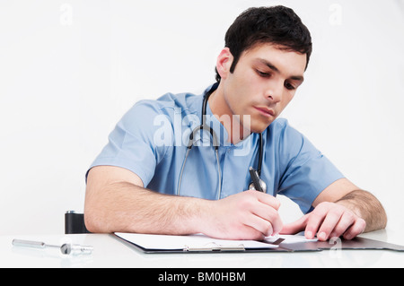 Arzt an einem Tisch sitzen und schreiben in eine Datei Stockfoto