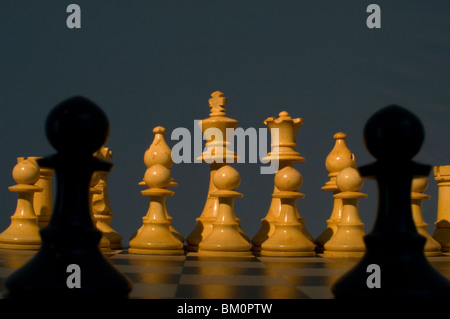 Schach. Zwei schwarze Bauern Silhouette vor weißen Figuren auf dem Schachbrett Stockfoto