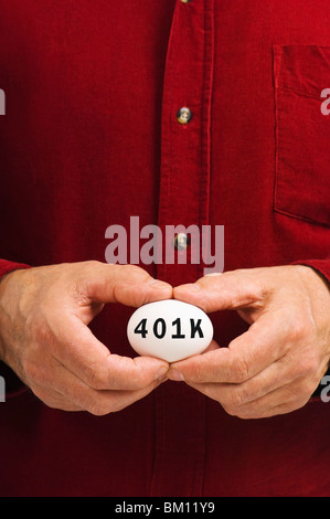 Ein Mann hält ein Ei mit 401 k darauf geschrieben. 401 k ist ein beliebtes Tool, Ersparnisse und Investitionen in den USA Stockfoto