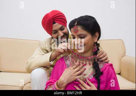 Mann, der an einer Halskette in seiner Frau Hals Stockfoto
