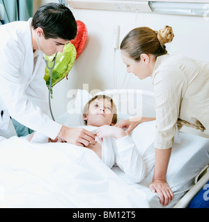 Junge auf einem Krankenhausbett von einem Arzt untersucht Stockfoto