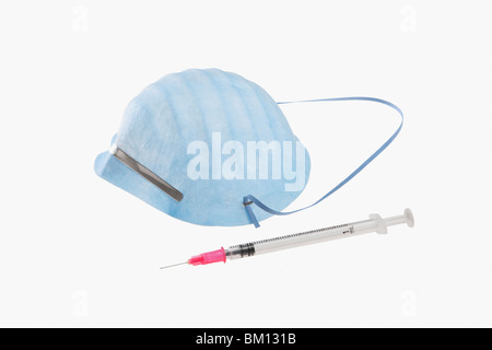 Nahaufnahme einer Spritze und einer Schweinegrippe-Maske Stockfoto