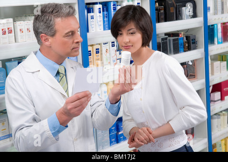 Apotheker hält eine Flasche Medizin und Beratung mit Kunden Stockfoto