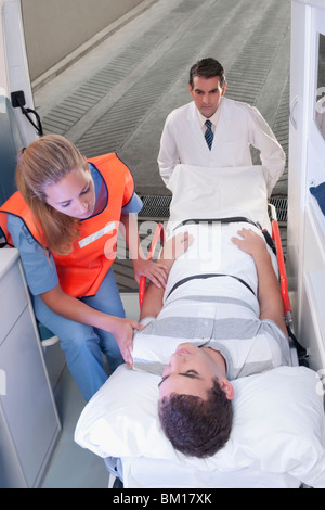 Führen eines Patienten auf einer Bahre in einen Krankenwagen Sanitäter Stockfoto